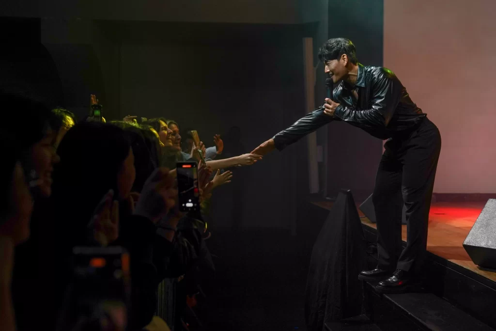 Kim Jong Kook tend le bras vers l'audience Sing the Wave